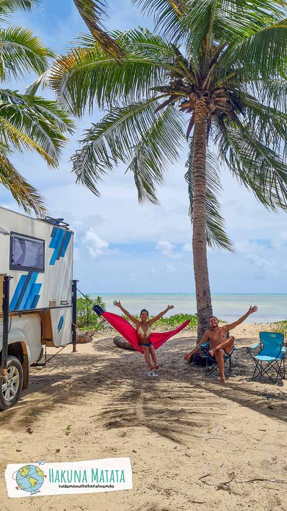 Un chico sentado en una silla y una chica en una hamaca en la playa, junto a un motorhome con vista al mar en Japaratinga