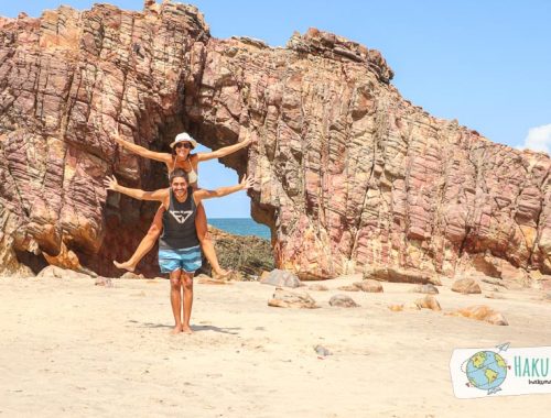 Dos personas en la playa bajo un arco de piedras, en Pedra Furada